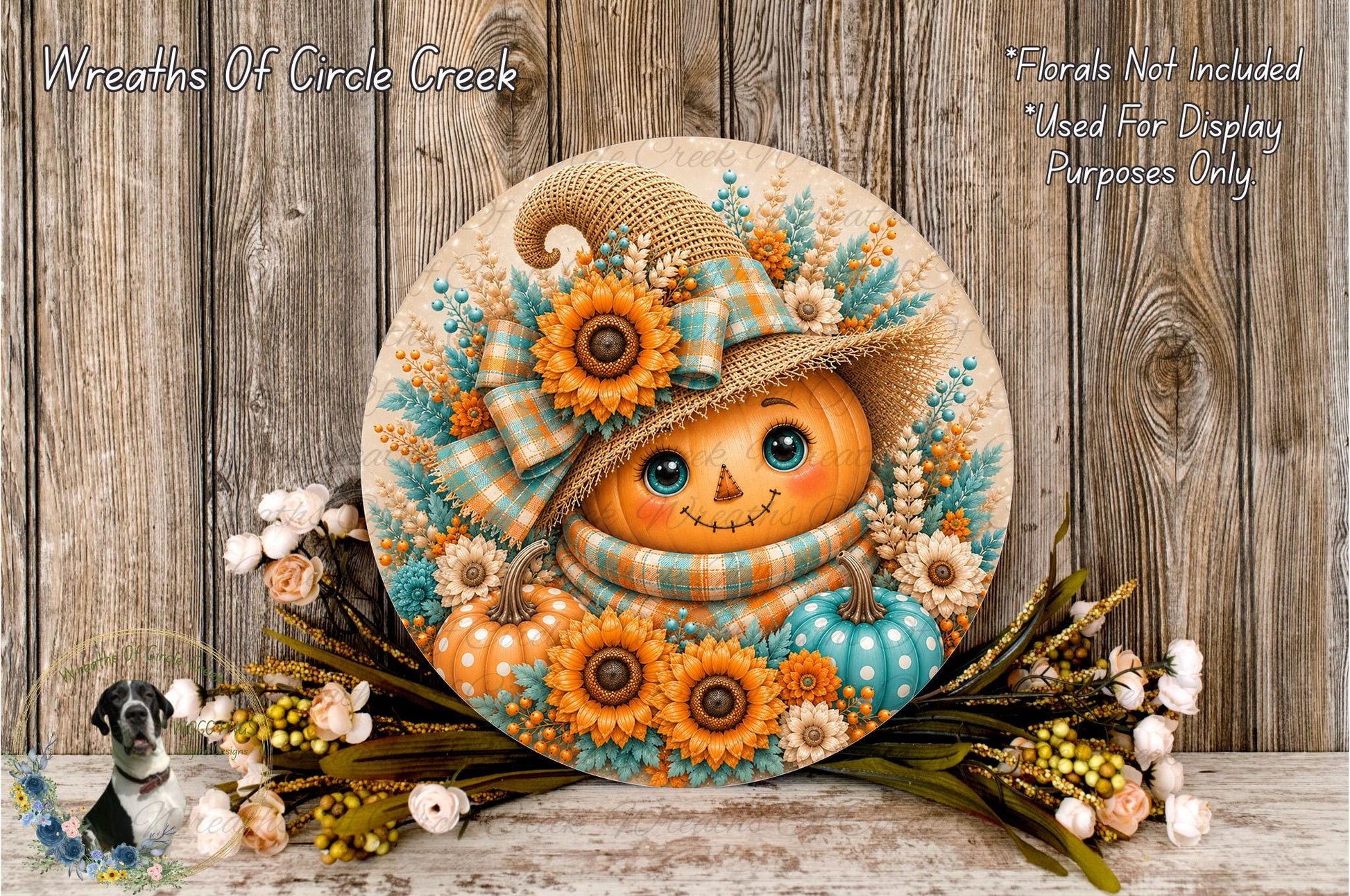 A decorative wreath featuring a pumpkin face with a hat and floral elements, placed on a wooden surface with a sprig of flowers and greenery.