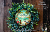 A wreath made of various green plants and flowers, with a circular plate in the center that says "Gulf of Mexico". The wreath is displayed on a wooden surface, and there is a small dog in the bottom right corner.