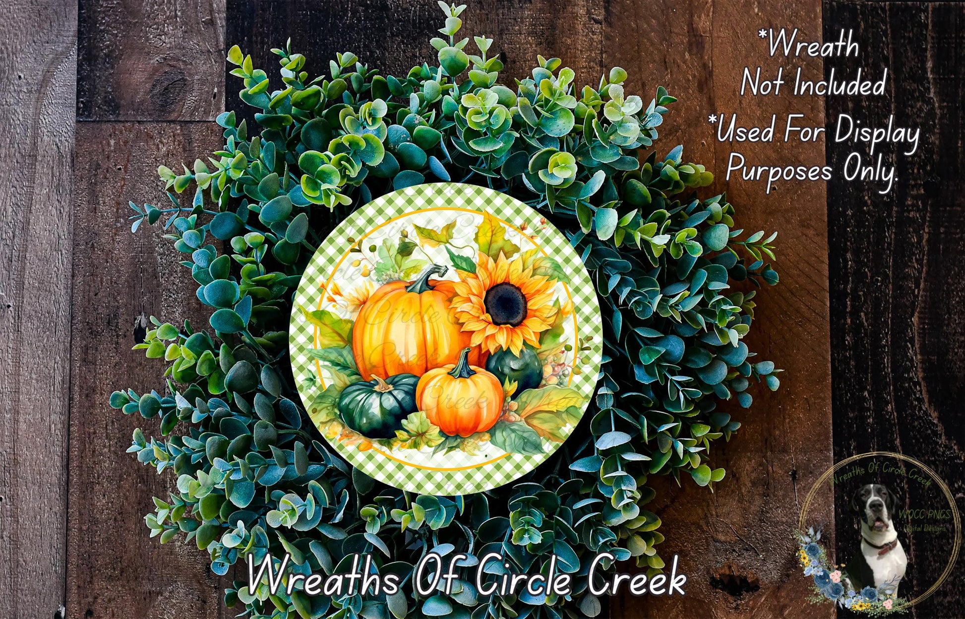 a wreath made of various autumn-themed elements, including pumpkins, gourds, and greenery. The wreath is displayed on a wooden surface, and there is a small dog in the bottom right corner of the image.
