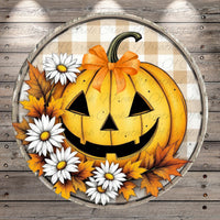 A Halloween-themed pumpkin decoration with a bow, surrounded by white daisies and autumn leaves, set against a wooden background.
