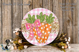 a decorative round sign with a pink bow and two orange carrots with white polka dots, placed on a wooden surface. The sign is surrounded by a floral arrangement of flowers and greenery.