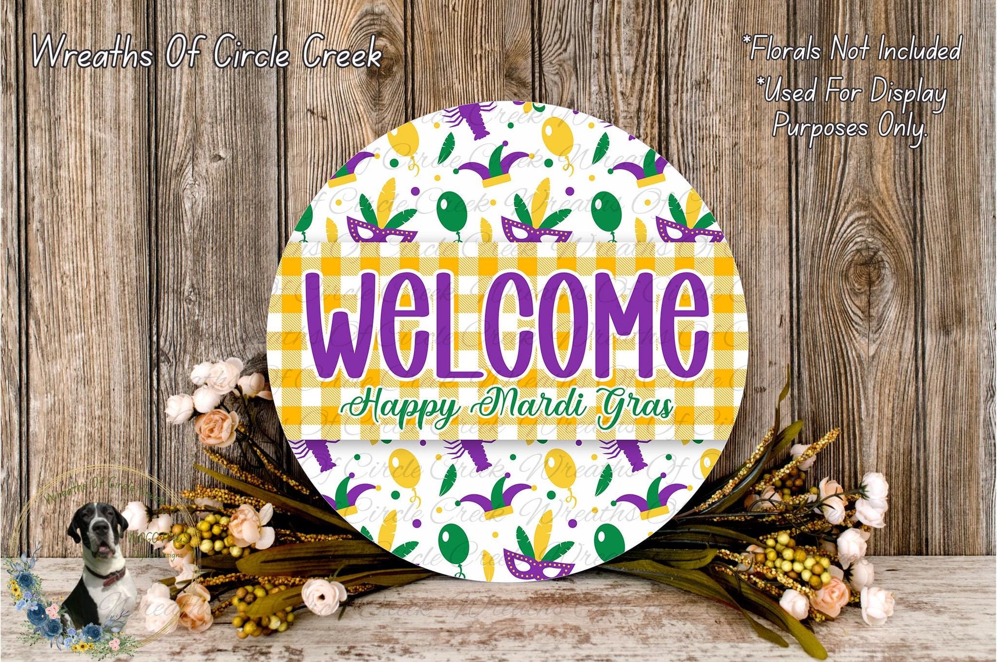 a circular sign with the text "Welcome Happy Mardi Gras" displayed on it, surrounded by a floral arrangement and a wooden background.