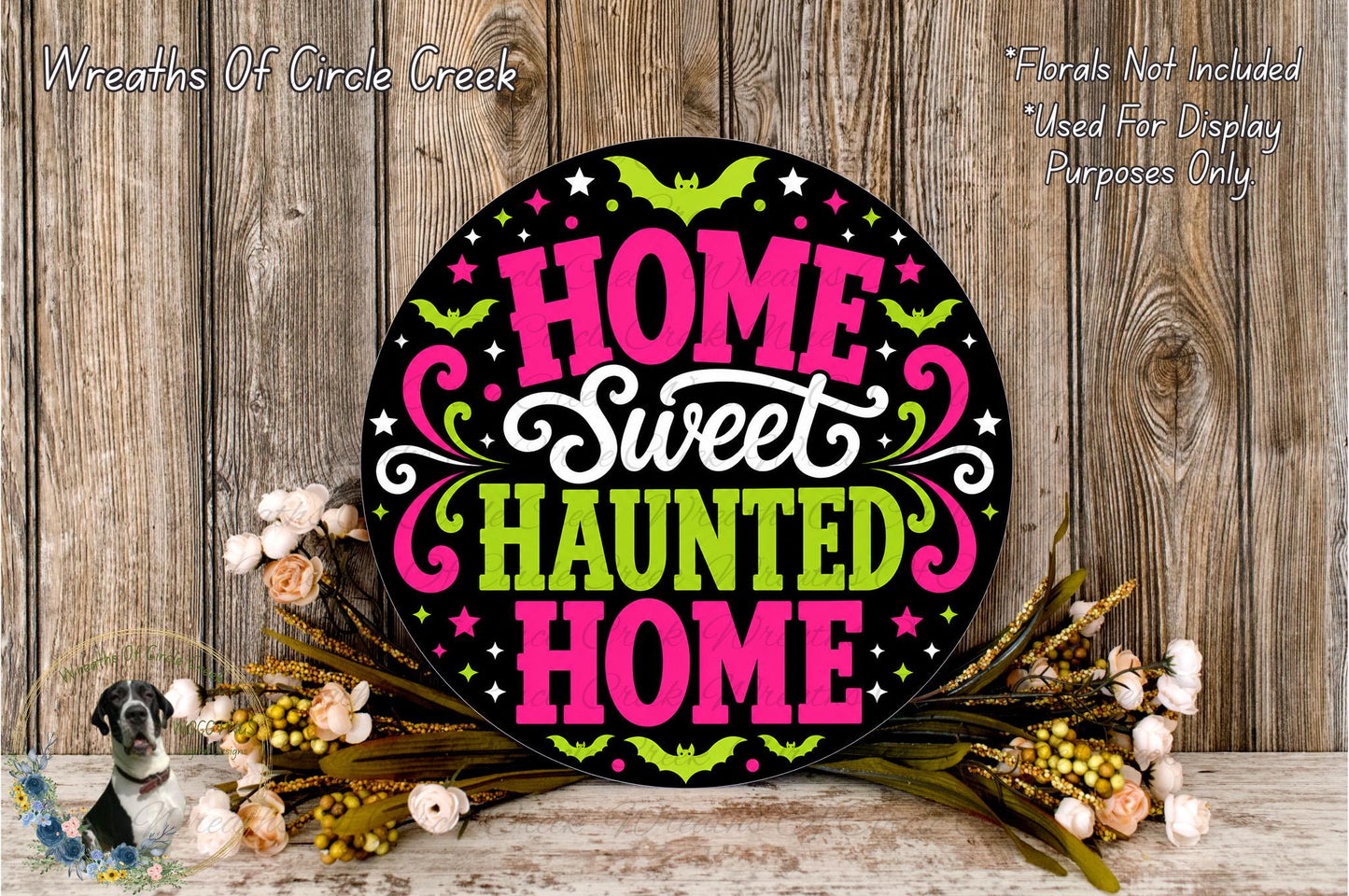 A decorative sign with the text "HOME SWEET HAUNTED HOME" in a circular design, surrounded by a floral arrangement and a wooden background.