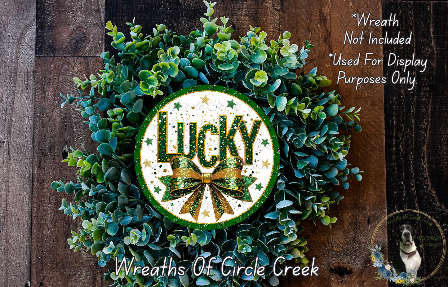 a wreath with the word "Lucky" prominently displayed in the center, surrounded by a lush green plant. The wreath is placed on a wooden surface, and there is a small dog visible in the bottom right corner of the image.