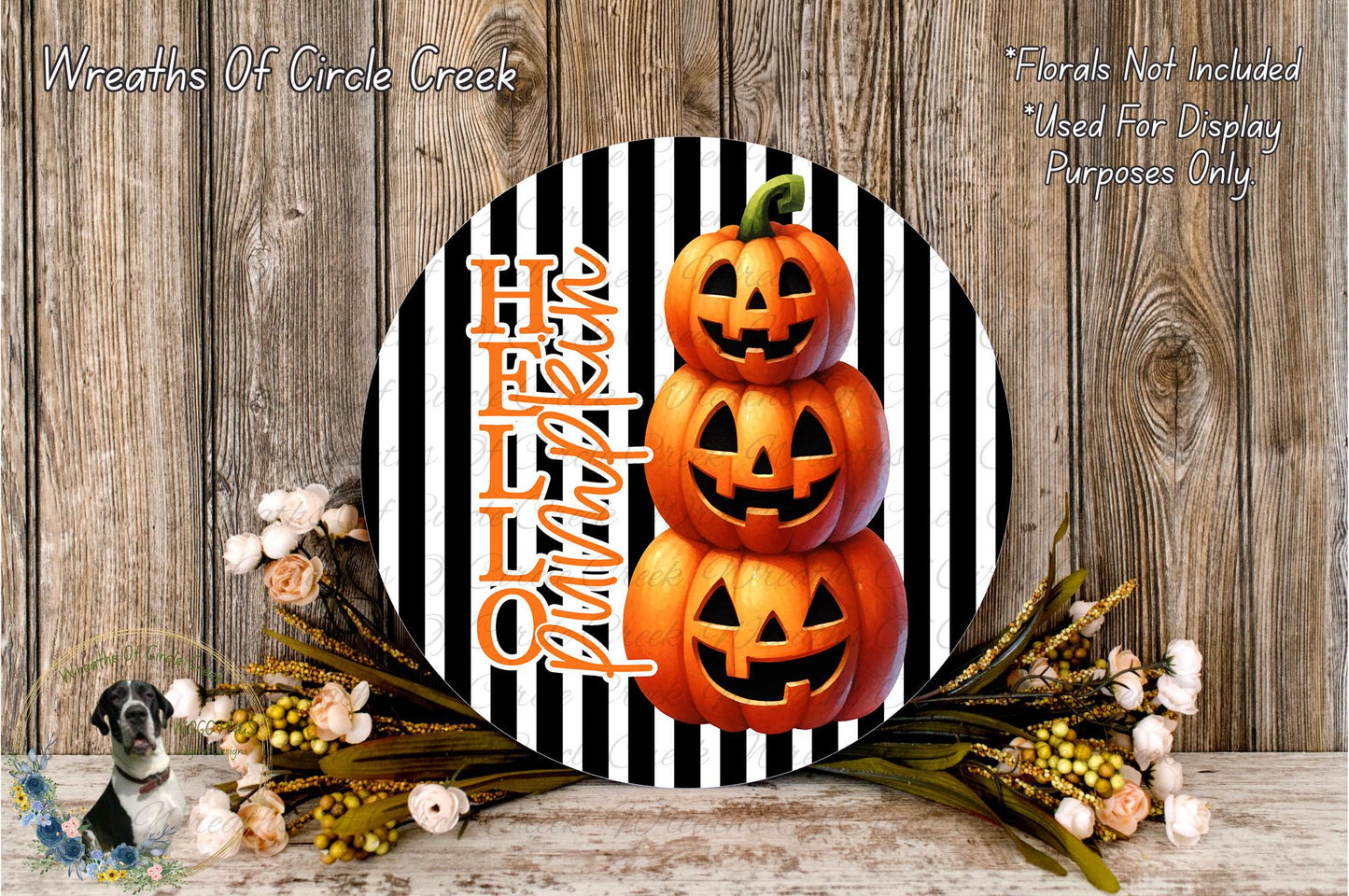 a Halloween-themed decoration with a black and white striped background, a circular arrangement of three jack-o'-lanterns, and a floral arrangement on the side.