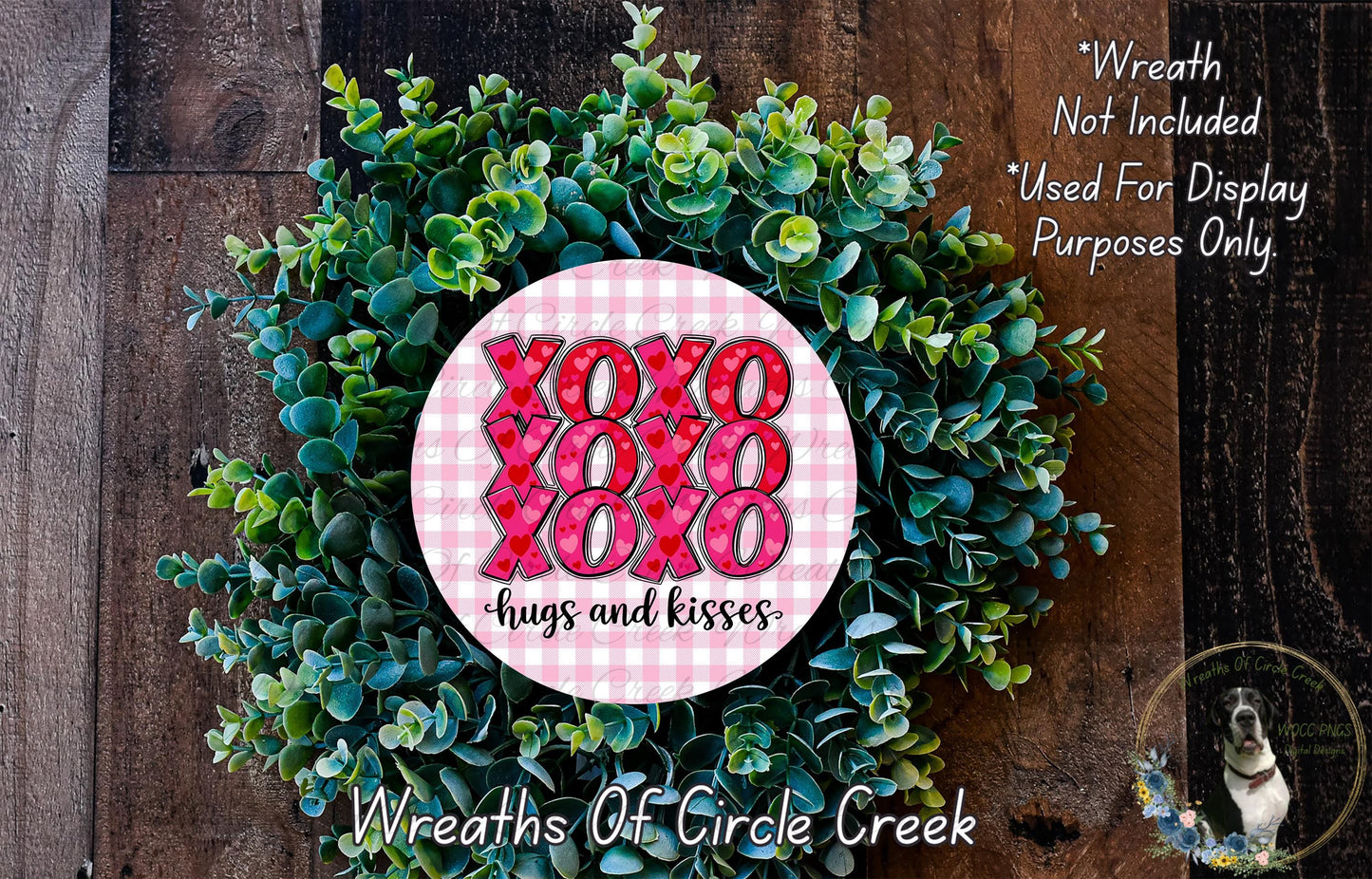 a wreath made of green leaves and a pink circular sign with the text "XOXO hugs and kisses" in the center.