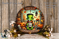 A Halloween-themed wreath featuring a green monster, a pumpkin, a skeleton, a cat, and a mug with the text "Hello Spooky Season!"