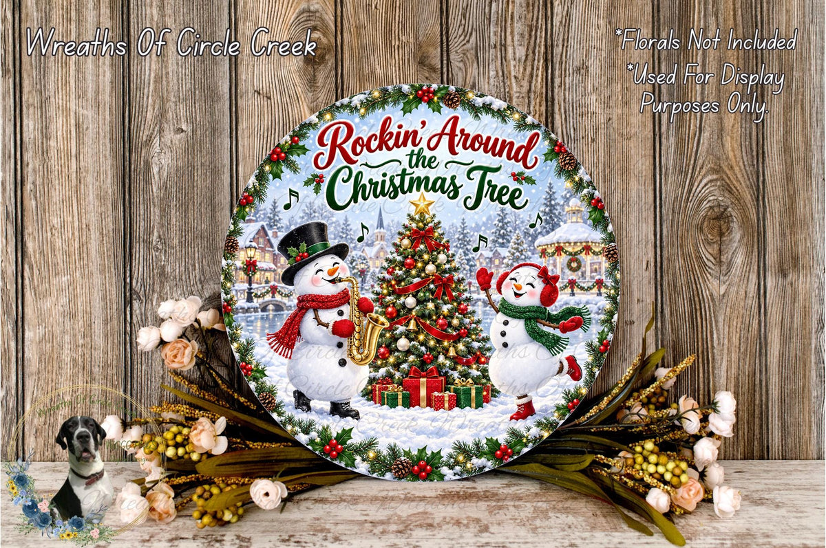A decorative Christmas wreath with a snowman and a Christmas tree, surrounded by flowers and greenery, against a wooden background.