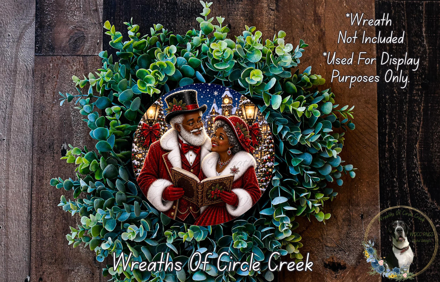 A wreath with a couple dressed in Santa Claus and reindeer, surrounded by greenery, and a small dog in the corner.