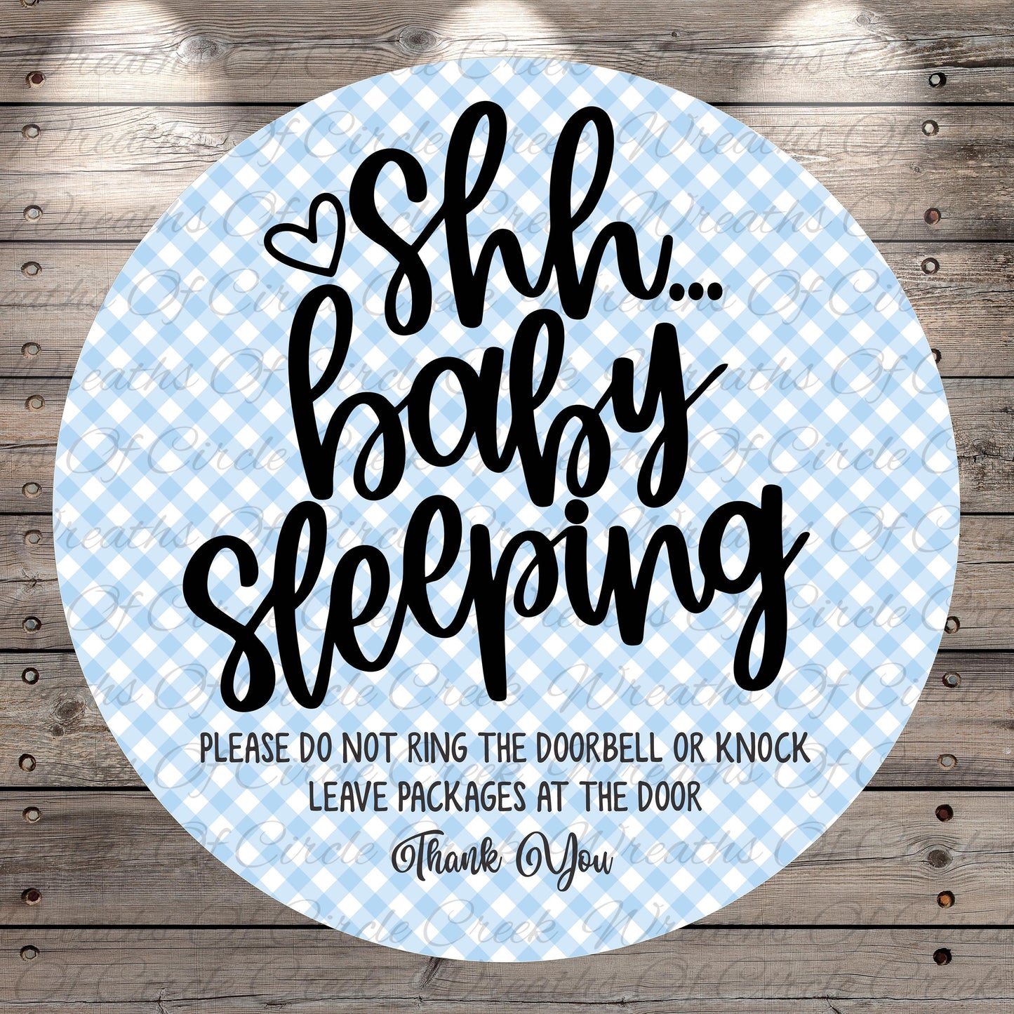 a circular sign with a blue and white checkered pattern, featuring a message that says "Shh... baby sleeping" in a playful and humorous tone.