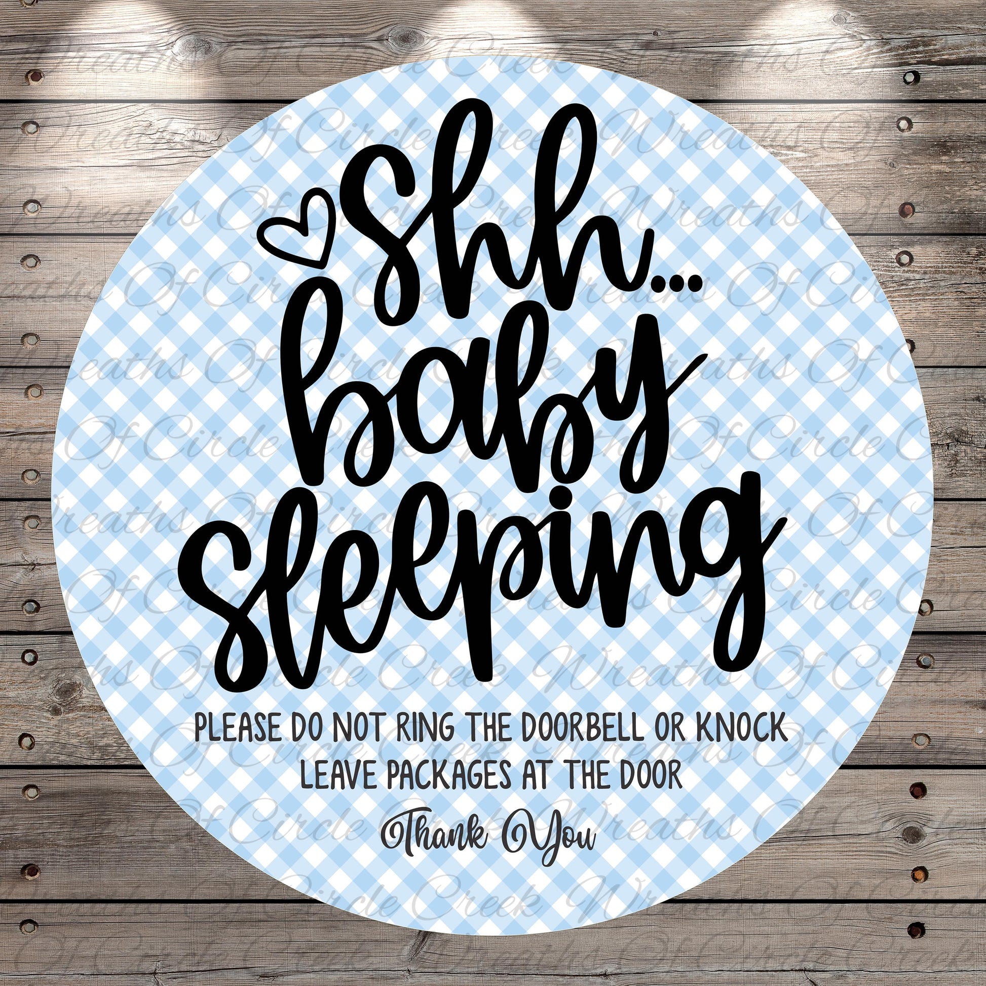 a circular sign with a blue and white checkered pattern, featuring a message that says "Shh... baby sleeping" in a playful and humorous tone.