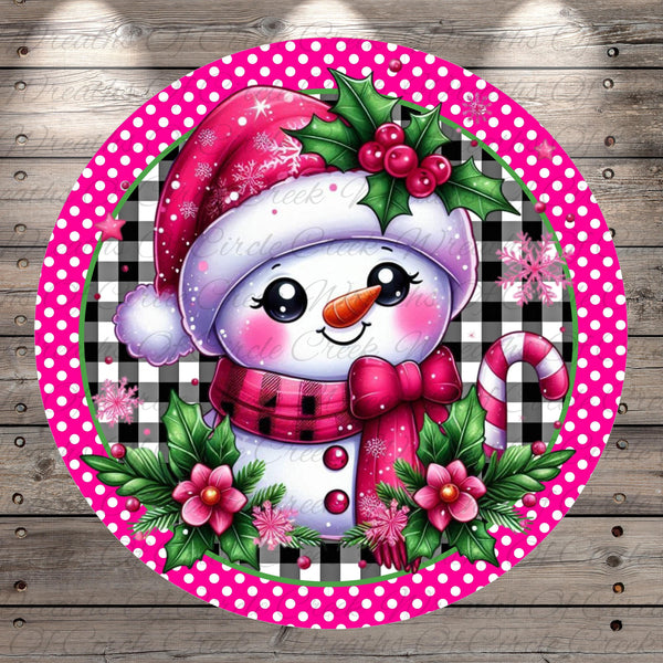 A cheerful snowman wearing a red hat, scarf, and bow, surrounded by pink flowers and green leaves, with a pink and white polka dot border.