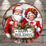 Santa Claus and Granny Claus, dressed in their traditional red outfits, are holding a sign that says "Happy Holidays".