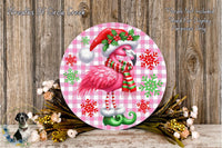 A pink flamingo wearing a Santa hat and scarf is surrounded by snowflakes and greenery, with a wooden background.