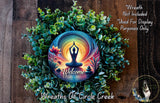 a wreath with a colorful design, including a Buddha symbol, surrounded by greenery and flowers. The wreath is placed on a wooden surface, and there is a text overlay that reads "Welcome Wreath Not Included * Used For Display Purposes Only".