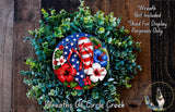 a wreath made of various greenery and flowers, including red and white flowers, and a pair of flip-flops. The wreath is displayed on a wooden surface, and there is a small dog in the background.