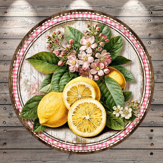 A round wooden platter with a pink and white checkered border, containing a vibrant arrangement of lemons, flowers, and leaves.
