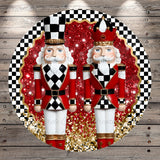 A circular arrangement of two nutcracker figurines, one wearing a red and white outfit and the other in a red and white outfit with a black and white hat, set against a background of red and gold glitter and a black and white checkered pattern.