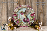 A decorative plate featuring a colorful hummingbird surrounded by a floral wreath, placed on a wooden surface.
