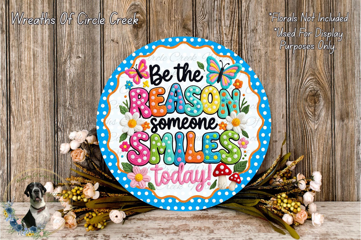 A decorative sign with the message "Be the reason someone smiles today!" surrounded by colorful flowers and a wooden background.