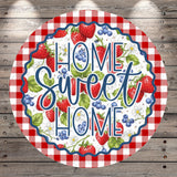 a round sign with a red and white checkered border, surrounded by a variety of colorful fruits and flowers. The sign prominently displays the text "HOME SWEET HOME" in a decorative font.