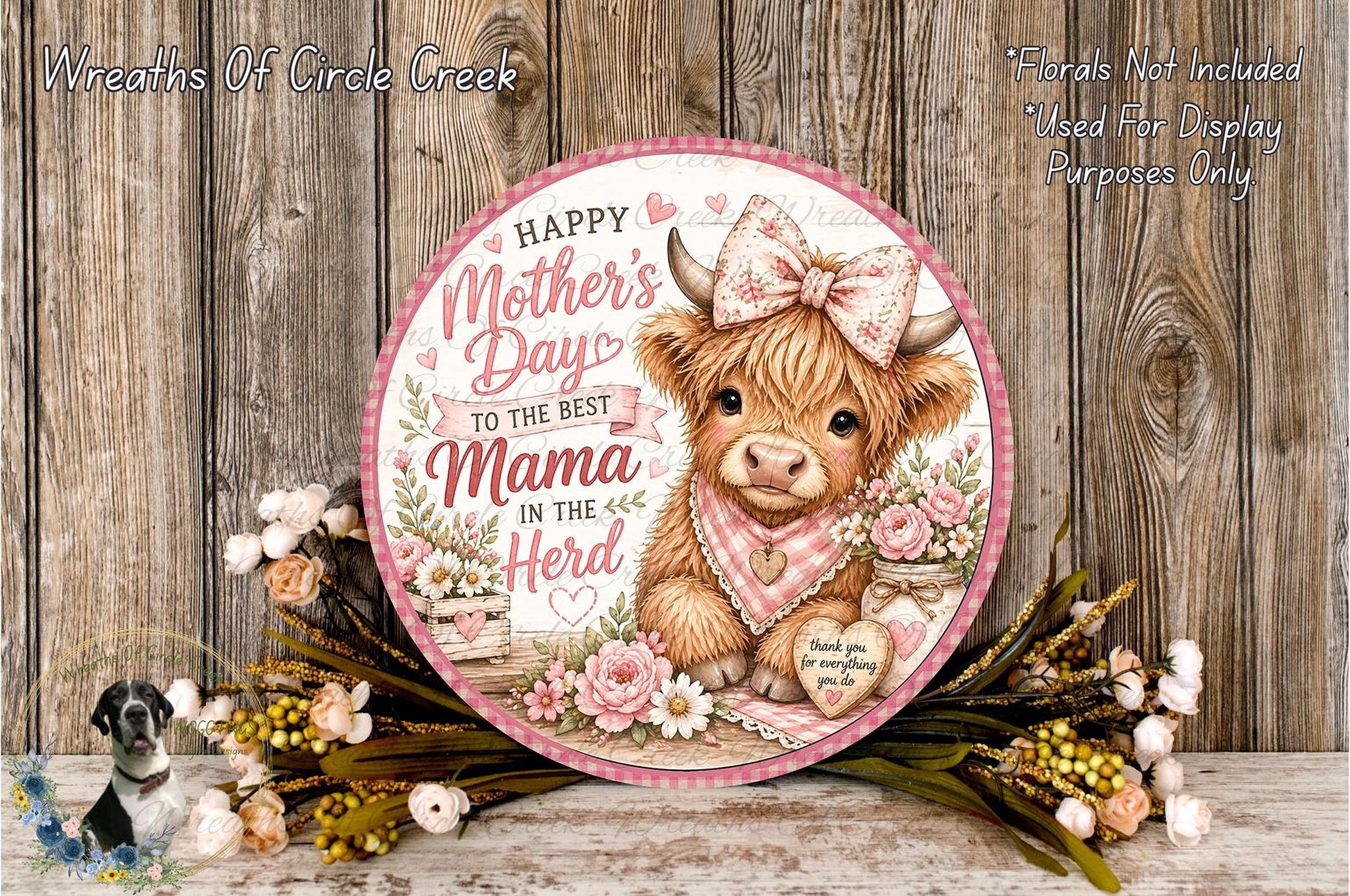 A round sign with a cartoon cow wearing a pink bow and surrounded by flowers, with the text "Happy Mother's Day to the best Mama in the herd" on it.