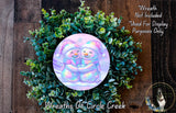 A wreath made of green plants and featuring two smiling snowmen.