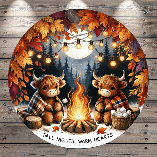 A cozy scene of two furry animals, possibly bison or cows, sitting around a campfire and enjoying the warmth and comfort of the fire. The background features a forest with autumn leaves, and string lights are strung up around the scene, creating a festive atmosphere. The text "FALL NIGHTS, WARM HEARTS" is displayed, suggesting a seasonal theme related to the fall season.