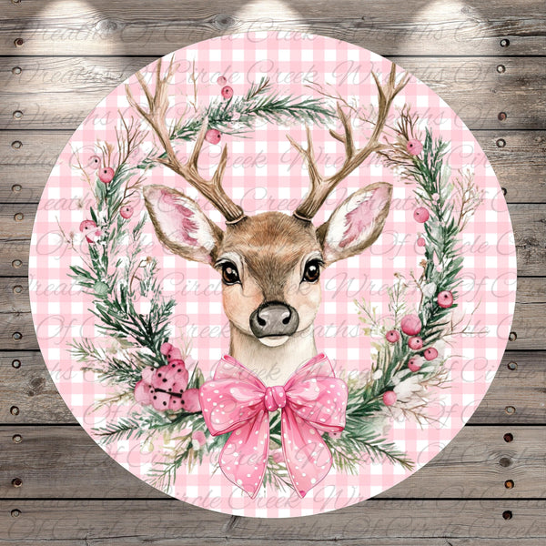 A round, pink and white checkered background with a detailed illustration of a deer's head wearing a pink bow, surrounded by a wreath of greenery and berries.