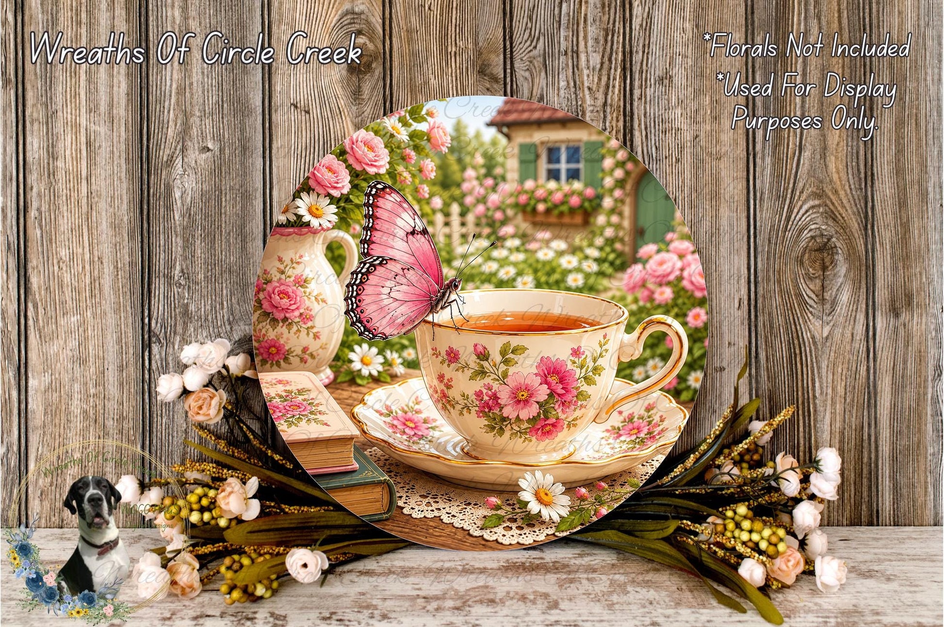 A floral arrangement with a teacup and saucer, a butterfly, and a vase of flowers, set against a wooden background.