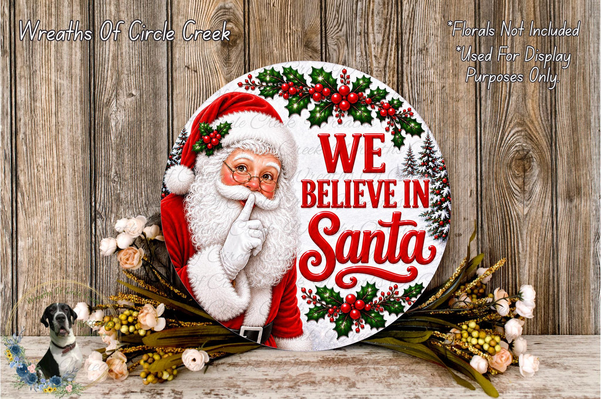 A round wooden sign with a Santa Claus figure and the text "We Believe in Santa" is displayed against a wooden background.