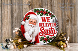 A round wooden sign with a Santa Claus figure and the text "We Believe in Santa" is displayed against a wooden background.