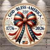 A circular wooden plaque with a large American flag design and a red, white, and blue ribbon bow. The plaque has the text "God Bless America" and "1776" and "2026" written on it.