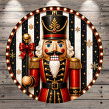 A nutcracker figure wearing a red and gold outfit, with a black hat and holding a red bow, is surrounded by a circular frame with a black and white striped background and red and white lights.