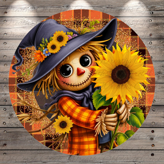 A cheerful scarecrow holding a sunflower, surrounded by a plaid pattern and autumnal elements.