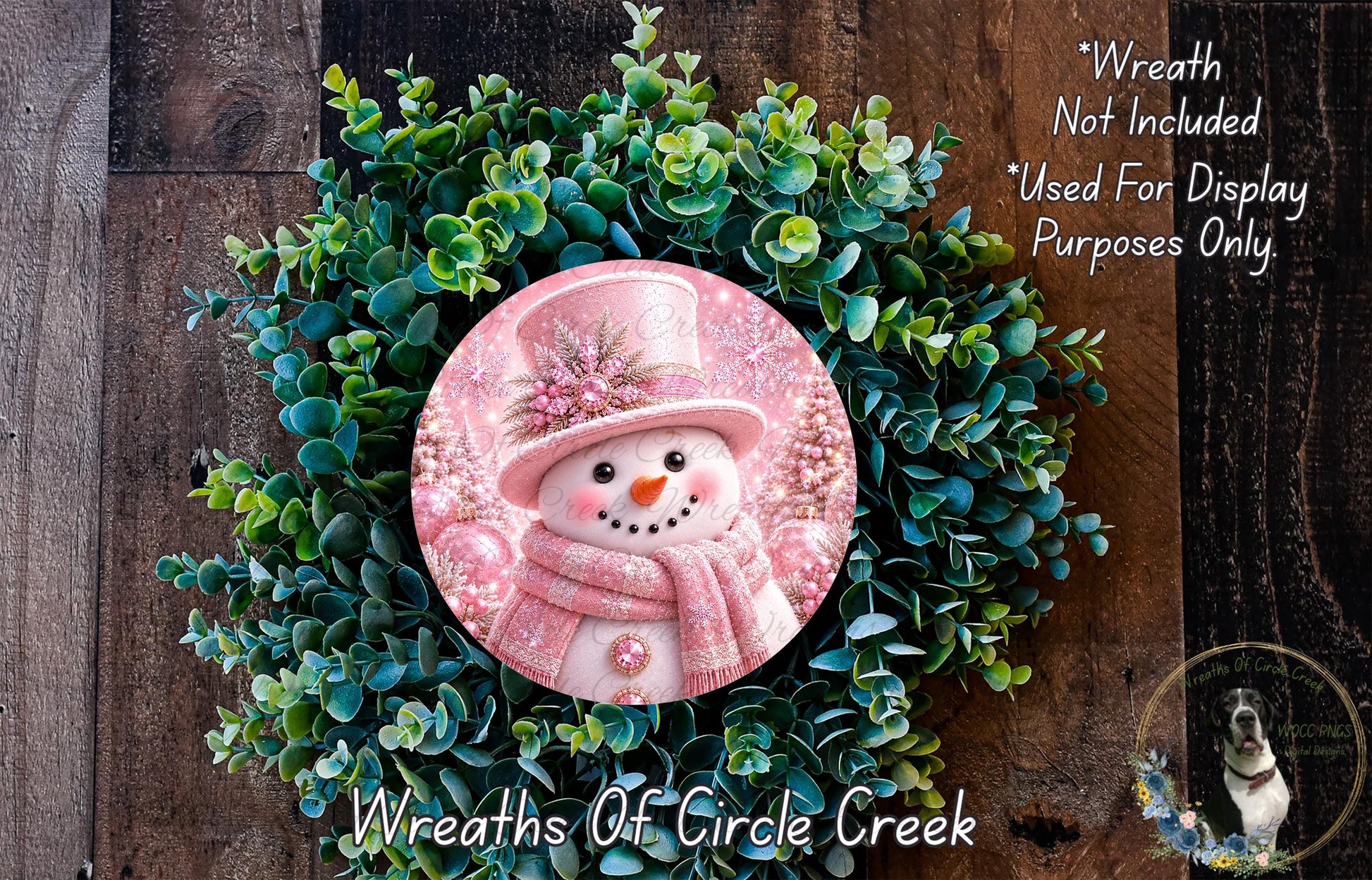 A wreath made of green foliage and a pink snowman figure, with a caption indicating that the wreath is not included in a display and is used for purposes only.