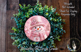 A wreath made of green foliage and a pink snowman figure, with a caption indicating that the wreath is not included in a display and is used for purposes only.