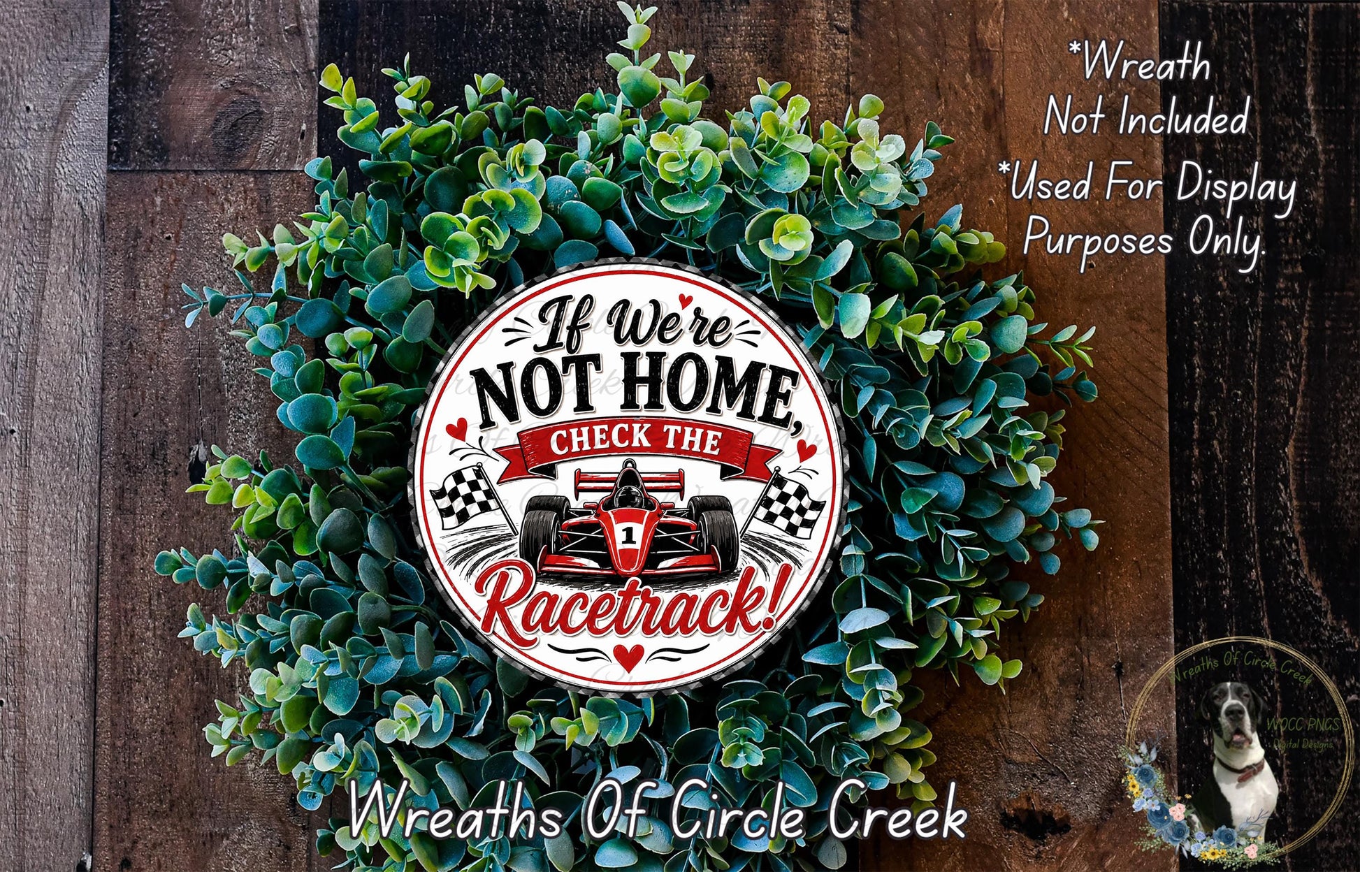 a wreath made of green leaves and a red and white racing car design, with the text "If we're not home, check the racetrack!" displayed on it.