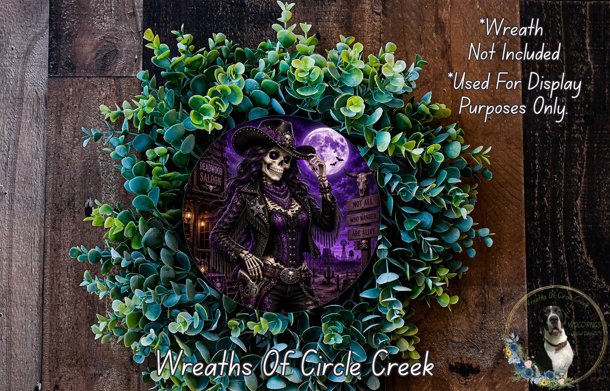a wreath with a skeleton wearing a cowboy hat, surrounded by green foliage and a full moon. The wreath is displayed on a wooden surface, and there is a small dog in the bottom right corner of the image.