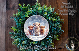 A wreath made of green foliage and featuring three small brown animals, likely cows, with a snowflake design. The wreath is displayed on a wooden surface, and there is a text overlay that reads "Wreath Not Included * Used For Display Purposes Only".