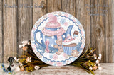 a decorative plate with a whimsical design, including a teapot, cupcakes, and a teddy bear, all set against a rustic wooden background.