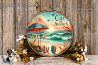 A round wooden plaque with a beach scene and an American flag, surrounded by flowers and placed on a wooden surface.