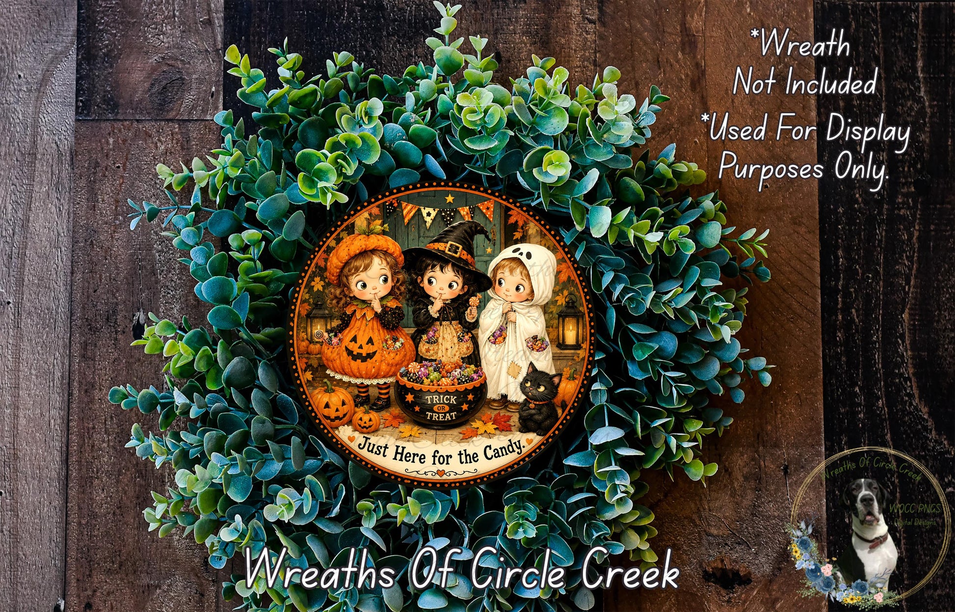 A wreath made of green leaves and featuring three cartoon girls dressed in Halloween costumes, with a pumpkin and a candy bowl. The wreath is displayed on a wooden surface, and there is a text overlay that reads "Wreath Not Included * Used For Display Purposes Only".