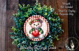 A wreath made of green leaves and a red heart, featuring a teddy bear holding a heart.