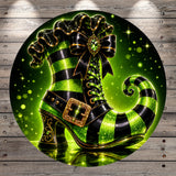 A green and black striped witch's boot with a gold buckle and bow, set against a background of green and black lights and sparkles.