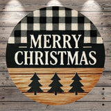 A circular wooden sign with the text "MERRY CHRISTMAS" in bold letters, surrounded by a checkered pattern and silhouettes of three Christmas trees.