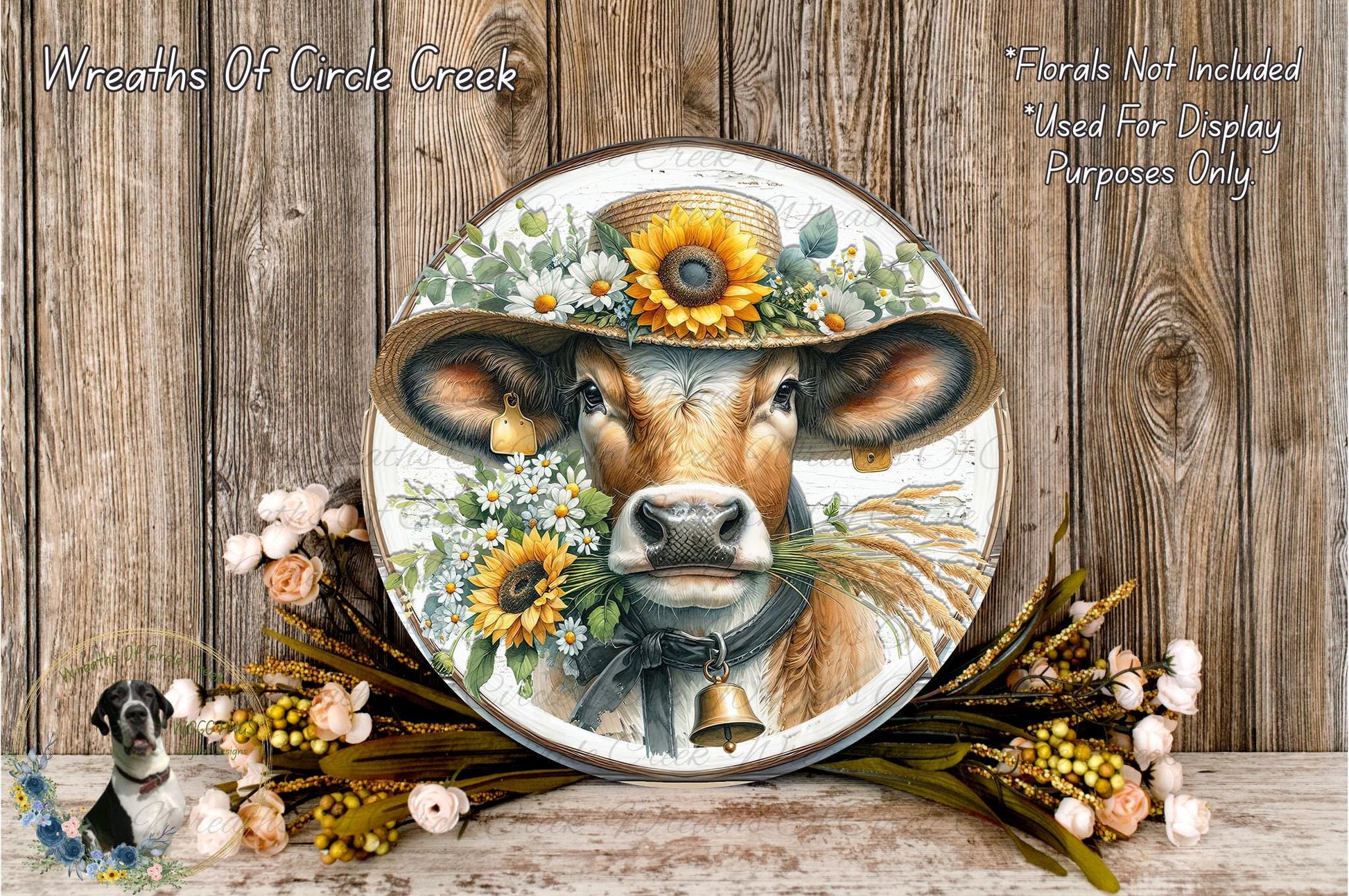A decorative plate featuring a cow wearing a sunflower hat, surrounded by flowers and a bell, placed on a wooden surface.