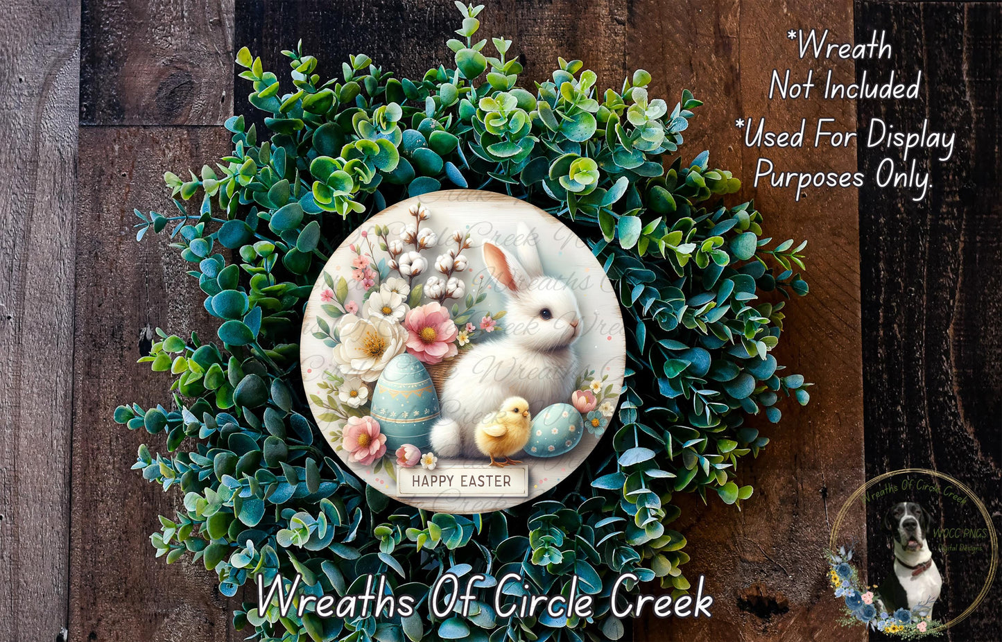 a wreath with a white rabbit and Easter eggs, surrounded by a lush green wreath. The wreath is displayed on a wooden surface, and there is a small dog in the bottom right corner of the image.