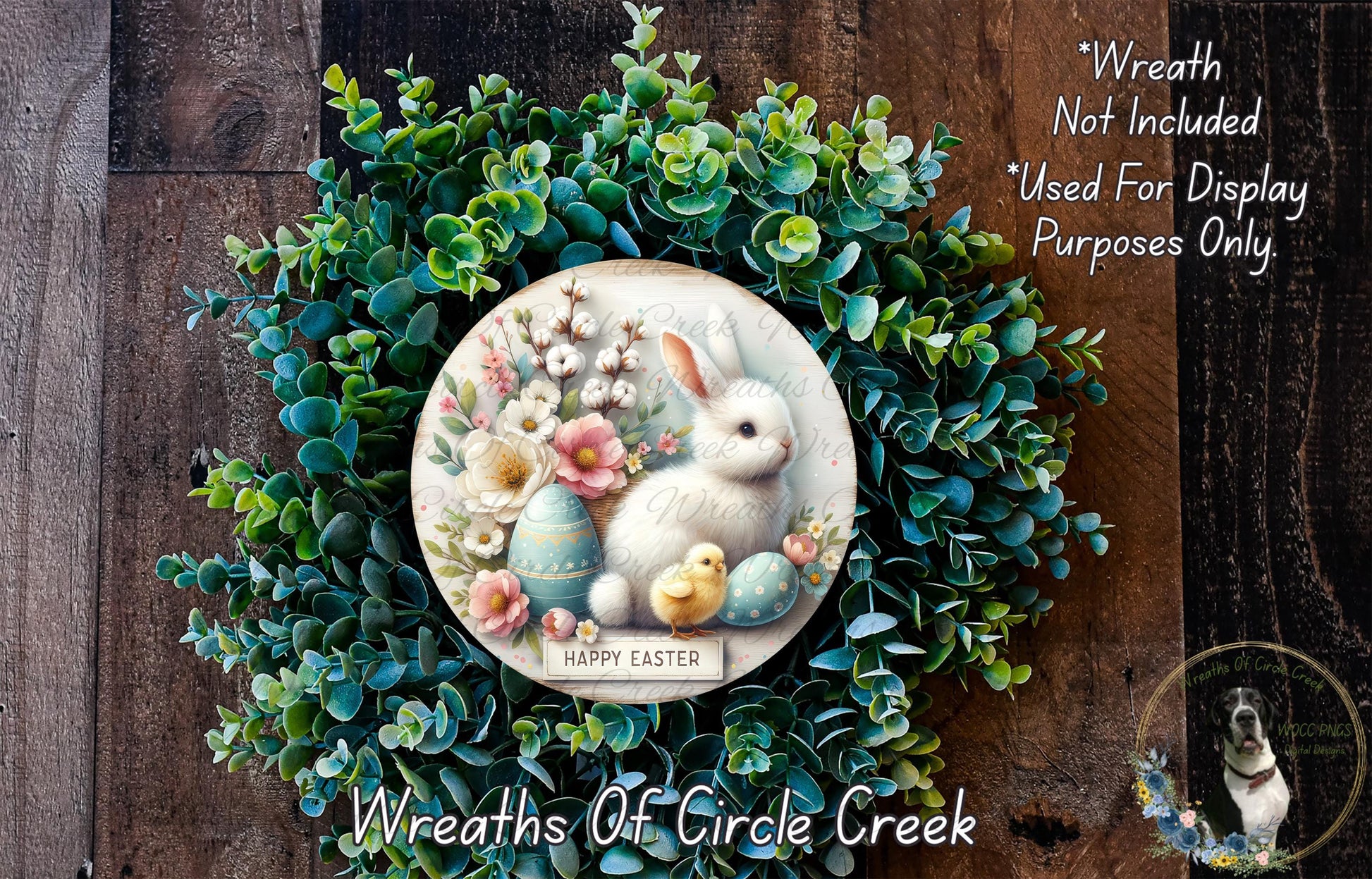 a wreath with a white rabbit and Easter eggs, surrounded by a lush green wreath. The wreath is displayed on a wooden surface, and there is a small dog in the bottom right corner of the image.
