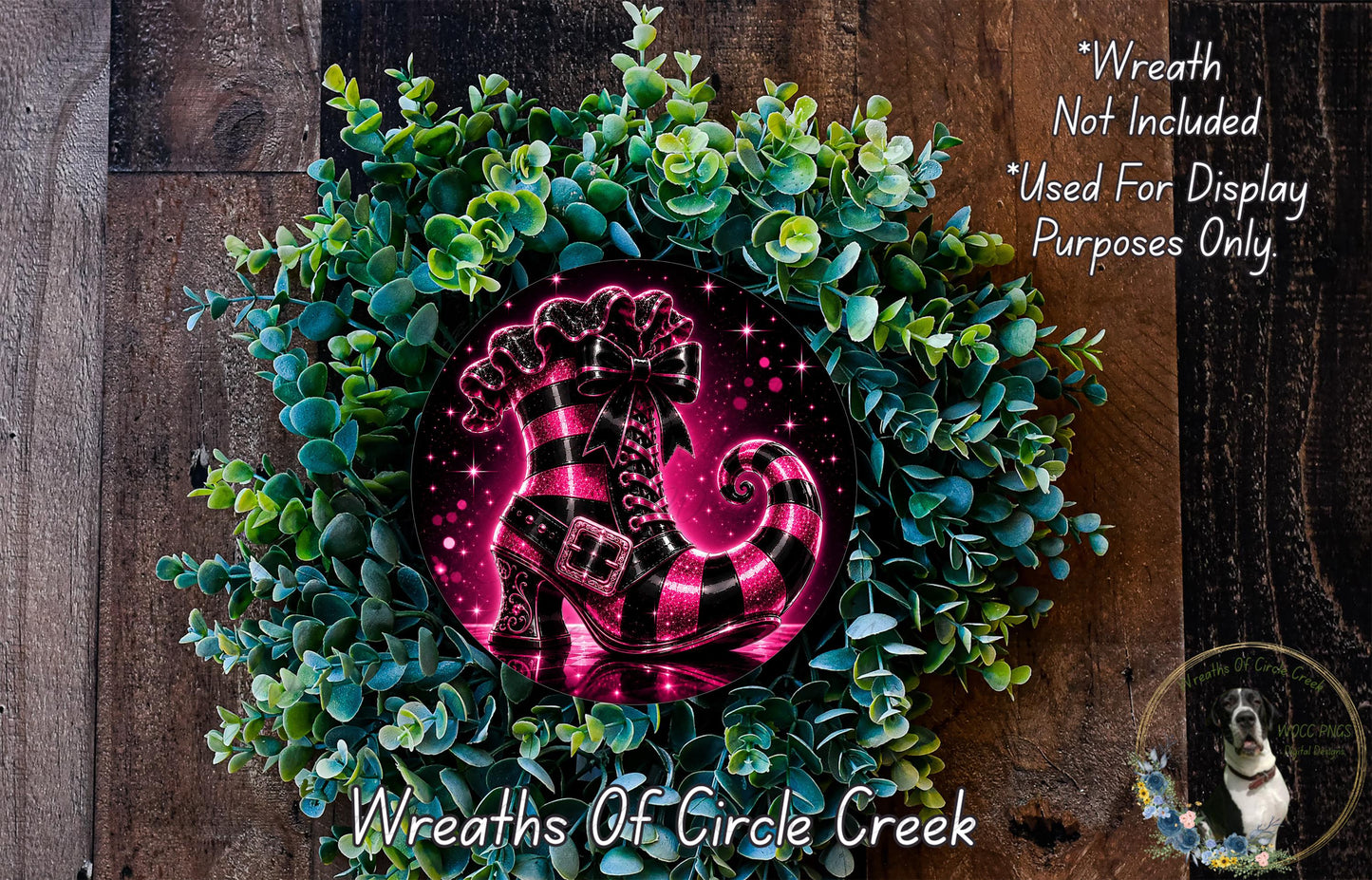 A wreath made of green leaves and a pink and black striped boot, with a starry background, is displayed on a wooden surface.
